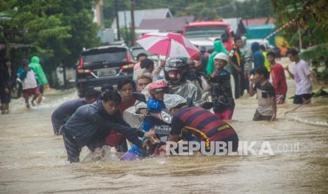 Sejumlah relawan membantu pengendara sepeda motor agar tidak terbawa arus saat melintas di Jalan Ahmad Yani, Kabupaten Banjar, Kalimantan Selatan, Jumat (15/1/2021). Gubernur Kalimantan Selatan Sahbirin Noor menyatakan peningkatan status siaga darurat menjadi tanggap darurat, keputusan itu diambil mengingat musibah banjir yang terjadi semakin meluas di beberapa daerah di Provinsi Kalimantan Selatan.