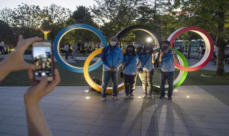 Sejumlah relawan Olimpiade Tokyo 2020 berfoto bersama di kawasan Stadion Nasional, Tokyo, Jepang, Kamis (22/7/2021).