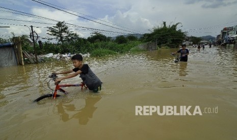 Sejumlah remaja menerobos banjir yang merendam di Jalan Raya Banjaran di Kelurahan Andir, Kecamatan Baleendah, Kabupaten Bandung, Rabu (8/3). 