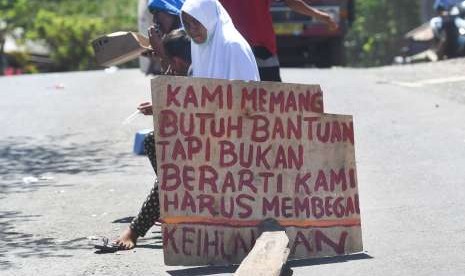 Sejumlah remaja pengungsi korban gempa bumi meminta bantuan di tengah jalan di sekitar lokasi tempat pengungsian darurat di Kayangan, Lombok Utara, NTB, Minggu (12/8). 