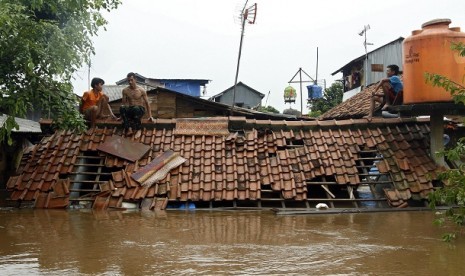 Sejumlah rumahwarga bertahan di atap rumah yang terendam banjir di bantaran sungai Ciliwung, Kampung Melayu, Jakarta Timur. Jumat (13/1). 