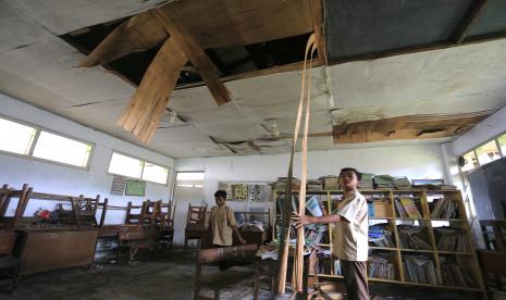 Sejumlah siswa berada di ruang perpustakaan yang rusak di SDN 2 Pawidean, Jatibarang, Indramayu, Jawa Barat, Jumat (14/1/2022). Sebanyak tiga ruang kelas dan satu ruang perpustakaan di sekolah itu plafonnya roboh serta kondisi atapnya rapuh dan tidak layak digunakan.