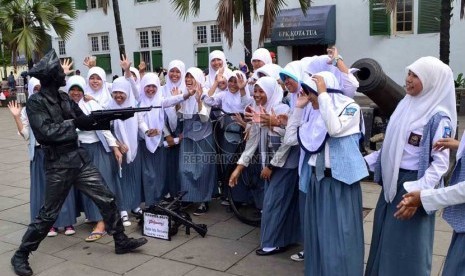   Sejumlah siswa berfoto bersama dengan Idris,sang manusia patung di Kota Tua, Jakarta Barat, Senin (25/2).   (Republika/Agung Supriyanto)