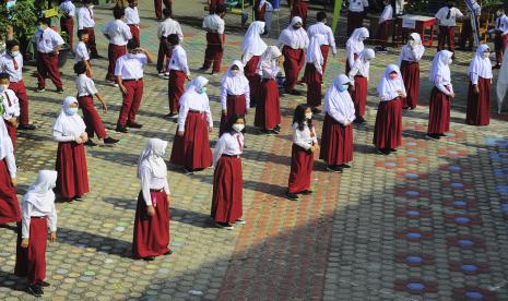 Sejumlah siswa berjemur dalam pengawasan guru di halaman sekolah sambil mengenakan masker saat hari pertama dimulainya kembali pembelajaran tatap muka.