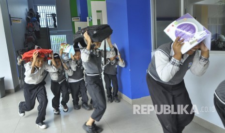 Sejumlah siswa berlari untuk menyelamatkan diri dari reruntuhan saat simulasi kebakaran dan gempa bumi di SD El Fitrah, Jalan Cibodas, Kota Bandung, Rabu (26/4).