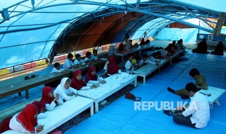 Sejumlah siswa dan siswi sekolah dasar mengikuti proses belajar di tenda pengungsian sementara di lapangan upacara Merdeka, Kabupaten Mamasa, Sulawesi Barat, Senin (26/11/2018). 