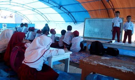 Sejumlah siswa dan siswi sekolah dasar mengikuti proses belajar di tenda pengungsian sementara di lapangan upacara Merdeka, Kabupaten Mamasa, Sulawesi Barat, Senin (26/11). 