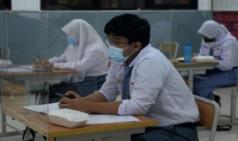 Sejumlah siswa dengan menjaga jarak dan menggunakan meja bersekat mengikuti persiapan Kompetisi Sains Nasional di SMAN 81 Jakarta.