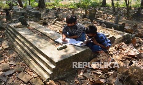 Sejumlah siswa kelas 6 SDN Sumberaji 2 mengerjakan tugas pelajaran sekolah secara daring atau online di kawasan makam Dusun Ngapus, Desa Sumberaji, Kecamatan Kabuh, Kabupaten Jombang, Jawa Timur, Sabtu (8/8/2020). Kawasan makam yang berada lebih tinggi dibandingkan pemukiman warga ini menjadi tempat belajar para siswa dari pagi hingga siang hari karena di lokasi tersebut yang memungkinkan mendapatkan sinyal jaringan internet untuk belajar online atau daring.