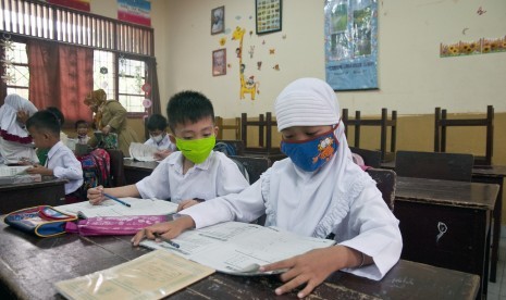 Sejumlah siswa kelas I SDN 15 mengenakan masker saat hari pertama sekolah kembali aktif di Kota Pekanbaru, Riau, Senin (5/10). 