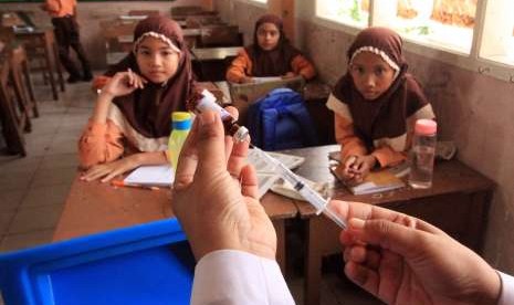 Sejumlah siswa melihat petugas kesehatan mengisi jarum suntik dengan vaksin Measles Rubella (MR) di SDN 1 Lhokseumawe, Aceh, Sabtu (4/8).