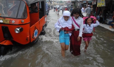   Sejumlah siswa melintas di atas genangan banjir ROB di kawasan Pluit, Jakarta Utara, Jumat (18/10).   ( Rakhmawaty La'lang/Republika)