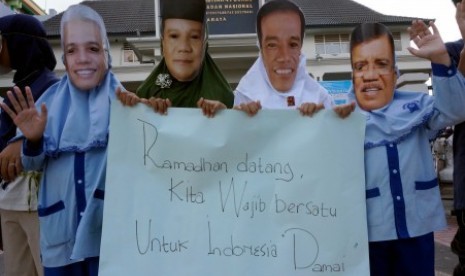 Sejumlah siswa memakai topeng Capres-Cawapres peserta Pemilu 2014, saat aksi simpatik 'Damai Jelang Ramadhan', di SD Muhammadiyah 4 Pucang, Surabaya, Rabu (25/6). 