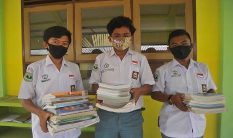 Sejumlah siswa membawa buku untuk belajar di rumah, di SMA 3 Pariaman, Sumatera Barat, Selasa (21/7). Pemkot Pariaman kembali menutup seluruh sekolah dan meniadakan belajar tatap muka pasca ditemukannya guru di daerah itu yang positif Covid-19. 