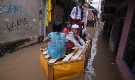   Sejumlah siswa menggunakan sampan untuk melintasi banjir yang merendam rumah mereka di Kampung Pulo, Jakarta Timur, Jumat (6/12).     (Republika/Rakhmawaty La'lang)