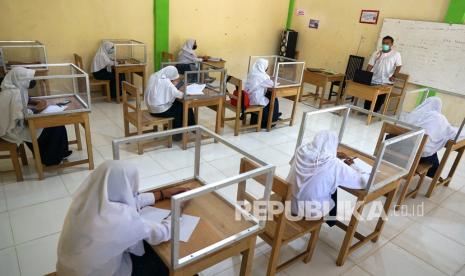 Sejumlah siswa mengikuti pelajaran tatap muka di Madrasah Tsanawiyah (MTs) Al Mujahidin Kabila, Kabupaten Bone Bolango, Gorontalo, Selasa (10/11/2020). Sekolah tersebut mulai menerapkan pelajaran tatap muka selain belajar daring dengan membuat bilik transparan di setiap meja, membatasi jumlah siswa di dalam kelas dan menerapkan protokol kesehatan secara ketat. 