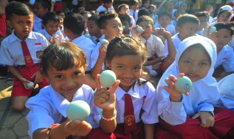 Sejumlah siswa menunjukkan telur bebek saat kegiatan Gerakan Gemar Makan Telur di Sekolah Dasar (ilustrasi). dalam rangka mendorong perkembangan riset dan penelitian di Indonesia, Yayasan Abhipraya Insan Cendekia Indonesia (YAICI) menggandeng 4 universitas terkemuka di Indonesia, diantaranya Universitas Indonesia (UI), Universitas Negeri Yogyakarta (UNY), Universitas Airlangga (UNAIR), dan Universitas Negeri Semarang (UNNES), untuk melakukan penelitian bersama terkait Konsumsi Susu dan Status Gizi Anak di Indonesia.