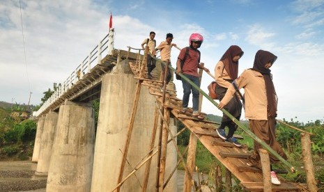 Sejumlah siswa menuruni titian darurat untuk menyeberangi Sungai Jragung.