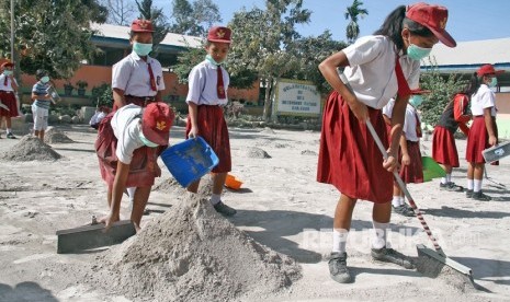 Sejumlah siswa SD membersihkan halaman sekolah pasca erupsi Gunung Sinabung, di Desa Payung, Karo, Sumatera Utara, Selasa (20/2). 