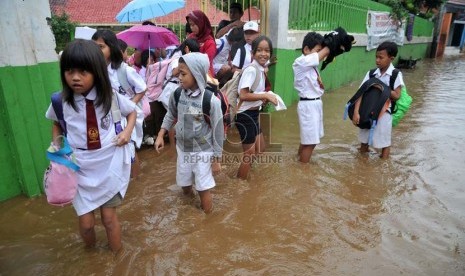   Sejumlah siswa SD terpaksa pulang sekolah melintasi banjir yang terjadi di kawasan Kampung Melayu Kecil, Jakarta,Senin (22/7).   (Republika/Prayogi)