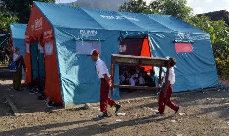 Sejumlah siswa SD Yayasan Madrasah Ibtidaiyah (MI) Darussalam Sukaraja mengangkat meja dan kursi dari sekolah mereka menuju tenda darurat untuk kegiatan belajar mengajar di Desa Sukaraja, Kabupaten Lampung Selatan, Lampung, Senin (7/1/2019). 