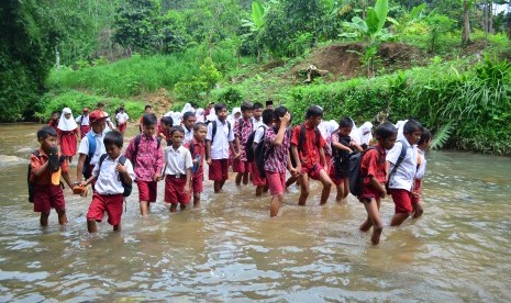 Sejumlah siswa SDN Cileungsir di Desa Ciandum, Kecamatan Cipatujah, Kabupaten Tasikmalaya menyeberang sungai Leuwi Karet sepulang dari sekolah, Kamis (12/2).