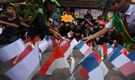 Sejumlah siswa SDN Kaliasin I Surabaya menyalakan lilin ketika menggelar aksi 'Pray for Paris' di halaman sekolahnya, Surabaya, Jawa Timur, Selasa (17/11).