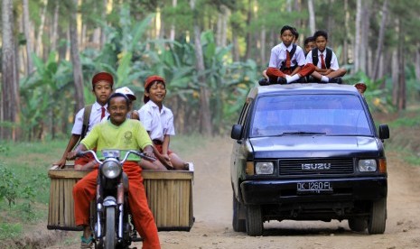 Sejumlah siswa sekolah dasar berangkat ke sekolah menaiki mobil angkut dan motor di Jayengan, Banyuwangi, Jawa Timur. (ilustrasi) 