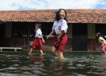 Sejumlah siswa sekolah dasar (SD) beraktifitas di bagian dari kompleks sekolah TK-SD-SMP Yayasan Pendidikan Esti Bakti yang terendam air di Jalan Raya Kapuk, Cengkareng, Jakarta Barat, selasa (20/3). (Republika/Aditya Pradana Putra)