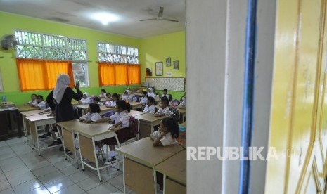 Sejumlah siswa-siswi murid baru kelas 1 memperhatikan gurunya saat memberi arahan pada hari pertama masuk sekolah di Sekolah Dasar Negeri (SDN) Pejaten Barat 10 Pagi, Jakarta Selatan, Senin (10/7).