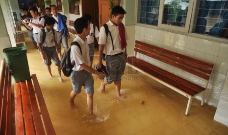   Sejumlah siswa SMA 8 melintasi genangan air yang merendam sekolah mereka di Jalan Bukit Duri, Jakarta Timur, Selasa (25/2). (Republika/Rakhmawaty)