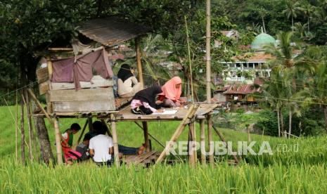 Sejumlah siswa SMA mengikuti kegiatan belajar mengajar dalam jaringan (daring) di area persawahan Bassaran, Desa Rante Mario, Kabupaten Enrekang, Sulawesi Selatan, Senin (3/8/2020). Siswa di daerah pelosok tersebut terpaksa mencari tempat tinggi untuk mengikuti kegiatan belajar mengajar daring selama pandemi COVID-19 akibat sulitnya akses internet di daerah itu. 