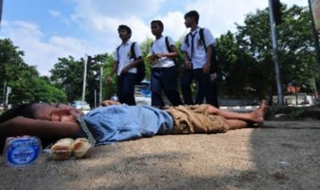 Sejumlah siswa SMP berjalan melintasi seorang anak gelandangan (putus sekolah) yang tertidur di kawasan Kebayoran Baru, Jakarta. 