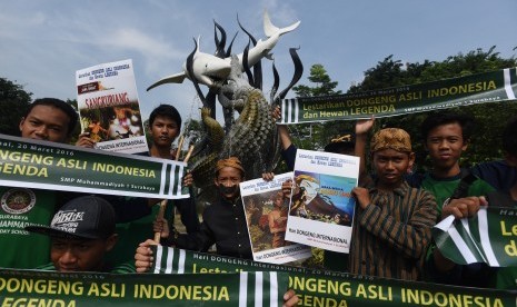 Sejumlah siswa SMP Muhammadiyah 1 Kapasan Surabaya membentangkan poster di depan patung Patung Suro dan Boyo di Kebun Binatang Surabaya saat aksi peringati Hari Dongeng Internasional, Surabaya, Jawa Timur, Jumat (18/3).