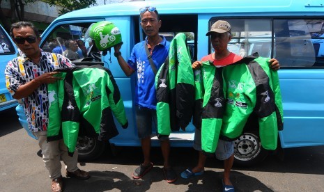 Sejumlah sopir angkutan kota Salatiga menunjukkan jaket hasil sitaan atribut pengendara transportasi daring atau online di Salatiga, Jawa Tengah, Senin (4/9). 