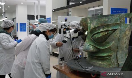 Sejumlah staf memperbaiki topeng perunggu yang ditemukan di situs reruntuhan Sanxingdui di provinsi Sichuan, China barat daya, dalam foto dokumentasi tanpa keterangan tanggal yang disiarkan pada Selasa (1/2/2022). Relik yang diperkirakan berusia 3.000 tahun itu memiliki lebar 131 cm, tinggi 71 cm, dan tebal 66 cm, serta bobot 65,5 kg dan dipamerkan ke publik di Gala TV Festival Musim Semi pada Senin (31/1).