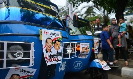 Sejumlah supir bajaj yang tergabung dalam Komunitas Bajaj DKI Jakarta menempelkan bajajnya dengan stiker bergambar Calon Presiden dan Calon Wakil Presiden Joko Widodo-Jusuf Kalla didepan Balai Kota, Jakarta, Selasa (24/6). 