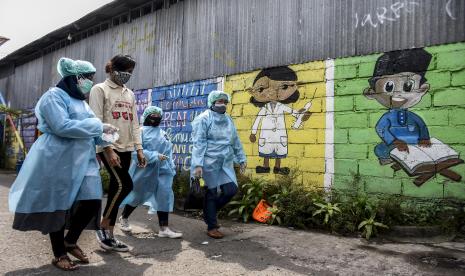 Sejumlah tenaga kesehatan bersama relawan berjalan untuk mendistribusikan obat bagi pasien Covid-19 yang sedang menjalani isolasi mandiri (isoman) di Antapani Kidul, Antapani, Kota Bandung.