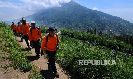 Sejumlah tim evakuasi gabungan melintas dijalur pendaki Gunung Merapi dengan berlatar belakang Gunung Merbabu di Selo, Boyolali, Jawa Tengah, Jumat (11/5).