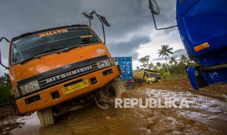 Sejumlah truk terperosok di Jalan Gubernur Sarkawi yang rusak di Kecamatan Sungai Tabuk, Kabupaten Banjar, Kalimantan Selatan, Senin (8/2). Pascabanjir ruas jalan nasional yang menghubungkan Provinsi Kalimantan Selatan dengan Provinsi Kalimantan Tengah tersebut rusak parah sehingga aktivitas ekonomi terganggu karena menurut pengakuan sopir truk, mereka harus berjibaku bahkan sampai tiga hari lamanya untuk melintas di jalan yang merupakan akses utama angkutan barang.