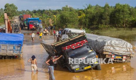 Sejumlah truk terperosok di Jalan Gubernur Sarkawi yang rusak di Kecamatan Sungai Tabuk, Kabupaten Banjar, Kalimantan Selatan, Senin (8/2). Presiden Joko Widodo (Jokowi) menyampaikan bahwa perlu penanganan komprehensif dari hulu ke hilir serta intervensi pemerintah daerah agar banjir tidak lagi terulang. 