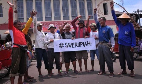 Sejumlah tukang becak membawa spanduk bertuliskan Save Rupiah di Pasar Gede, Solo, Jawa Tengah, Kamis (12/3).  (Antara/Yusuf Nugroho)