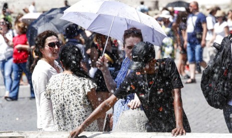 Sejumlah turis mendinginkan diri di dekat air mancur St. Peter Square di Vatikan, Sabtu (29/6). Italia mengeluarkan peringatan panas di 16 kota.