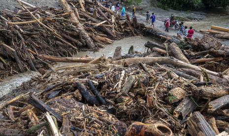 Sejumlah warga berada di antara tumpukan potongan kayu yang terbawa saat terjadi banjir bandang di Desa Rogo, Dolo Selatan, Sigi, Sulawesi Tengah.