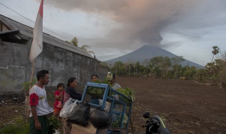 Sejumlah warga beraktivitas di sekitar rumahnya dengan latar belakang Gunung Agung meletus di Desa Datah yaitu desa yang termasuk dalam kawasan rawan bencana, Karangasem, Bali, Senin (27/11).