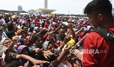 Sejumlah warga berdesakan untuk mengambil sembako gratis saat acara Untukmu Indonesia di kawasan Monas, Jakarta, Sabtu (28/4). 