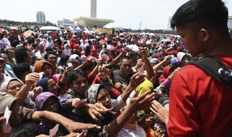 Sejumlah warga berdesakan untuk mengambil sembako gratis saat acara Untukmu Indonesia di kawasan Monas, Jakarta, Sabtu (28/4). 