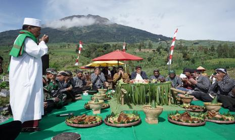 Sejumlah warga berdoa bersama saat tradisi Wiwit Tembakau di perladangan kawasan lereng Gunung Sumbing Cepit, Pagergunung, Bulu, Temanggung, Jawa Tengah, Rabu (3/8/2022). Masyarakat petani tembakau di wilayah Temanggung melangsungkan tradisi Wiwit Tembakau atau prosesi memulai panen tembakau secara berurutan di Gunung Prau, Gunung Sindoro dan Gunung Sumbing sebagai doa permohonan kepada Tuhan YME agar diberi kelancaran dan kesuksesan selama musim tembakau. 