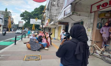 Sejumlah warga berfoto di tempat duduk yang menyerupai sepatu kelom geulis di trotoar Jalan KH Z Mustofa, Kota Tasikmalaya, yang sedang dalam penataan, Ahad (25/9/2022).