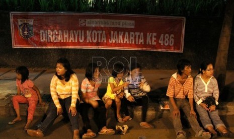   Sejumlah warga beristirahat karena lelah saat perayaan HUT Kota Jakarta ke-486 di Jalan MH Thamrin, Jakarta, Sabtu (22/6).  (Republika/Yasin Habibi)